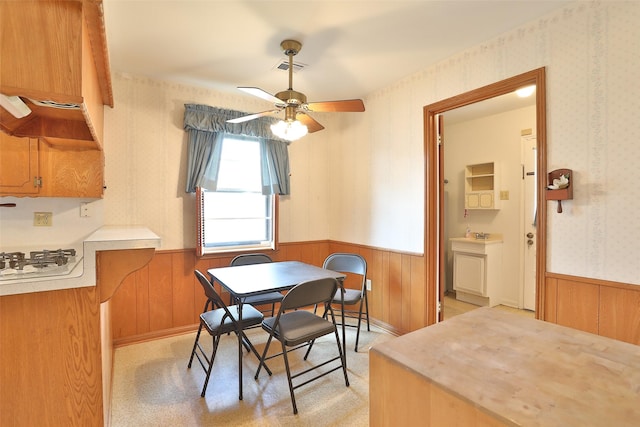 dining area with wainscoting, ceiling fan, visible vents, and wallpapered walls