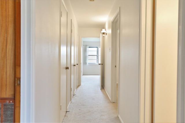 hall featuring baseboards and light colored carpet