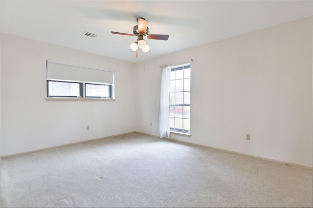 spare room with carpet floors, a ceiling fan, visible vents, and baseboards