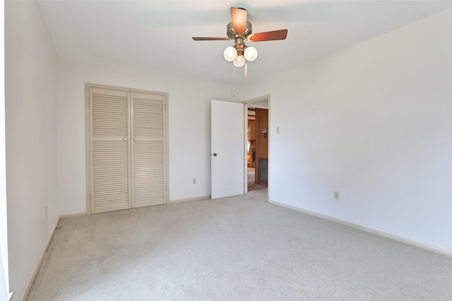 unfurnished bedroom with a closet, light colored carpet, ceiling fan, and baseboards