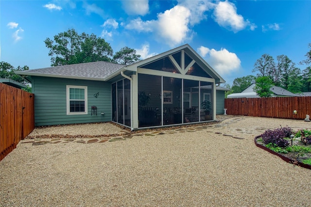 rear view of property with a sunroom, a fenced backyard, and a shingled roof