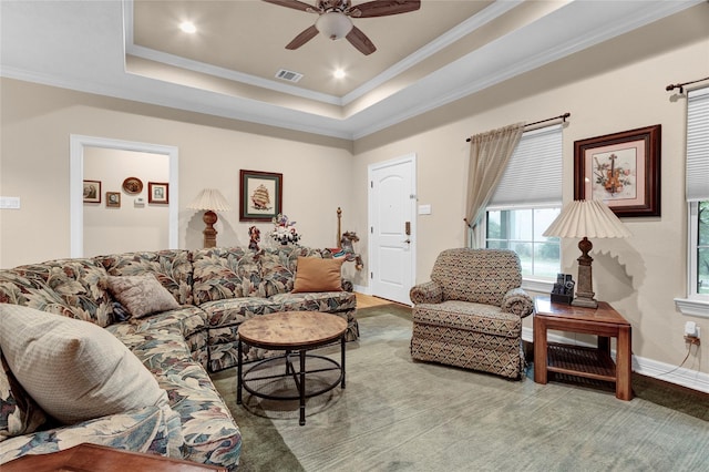 living room with ornamental molding, a tray ceiling, visible vents, and baseboards