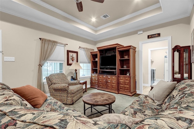 living area featuring ornamental molding, a tray ceiling, visible vents, and ceiling fan