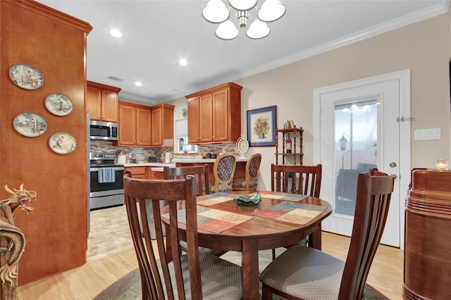 dining area with ornamental molding, light wood-type flooring, a chandelier, and visible vents