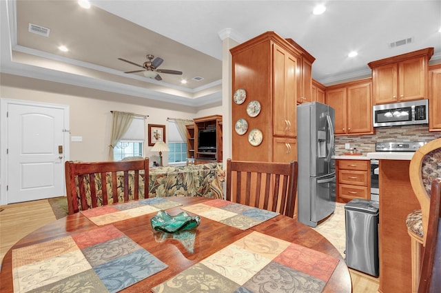 kitchen featuring a tray ceiling, appliances with stainless steel finishes, light countertops, and visible vents