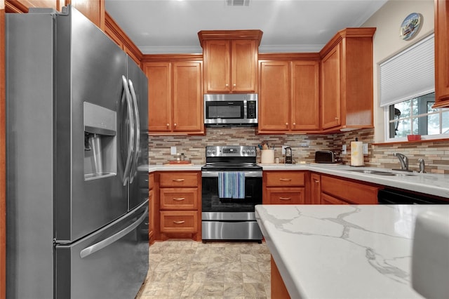 kitchen featuring light stone counters, a sink, visible vents, appliances with stainless steel finishes, and tasteful backsplash