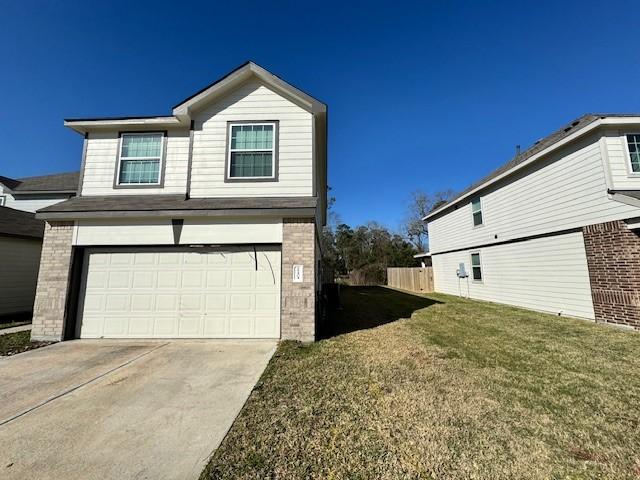 view of side of property featuring a yard, brick siding, driveway, and an attached garage