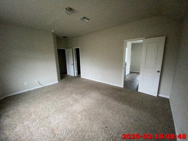 carpeted spare room featuring baseboards and visible vents