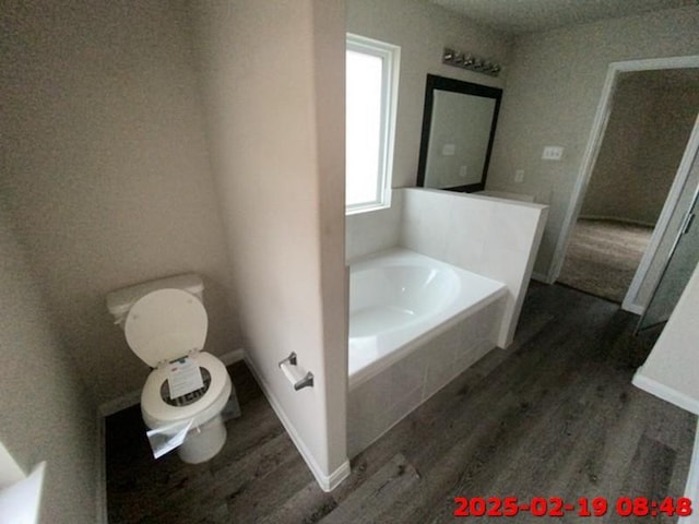 full bath with a bath, baseboards, toilet, and wood finished floors