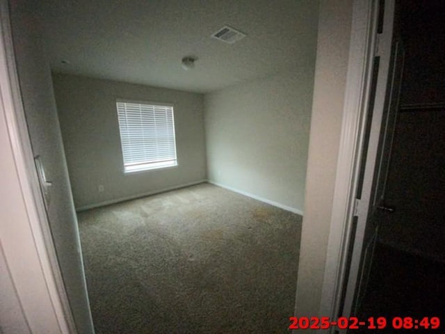 empty room featuring carpet floors, baseboards, and visible vents