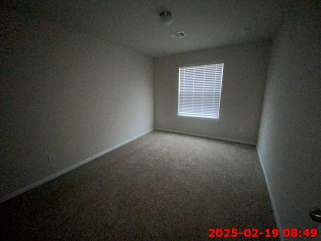 spare room featuring carpet, visible vents, and baseboards