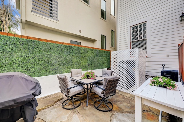 view of patio with outdoor dining space, grilling area, and fence