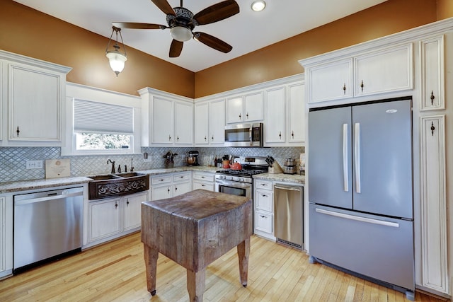 kitchen with a sink, stainless steel appliances, decorative backsplash, and a ceiling fan