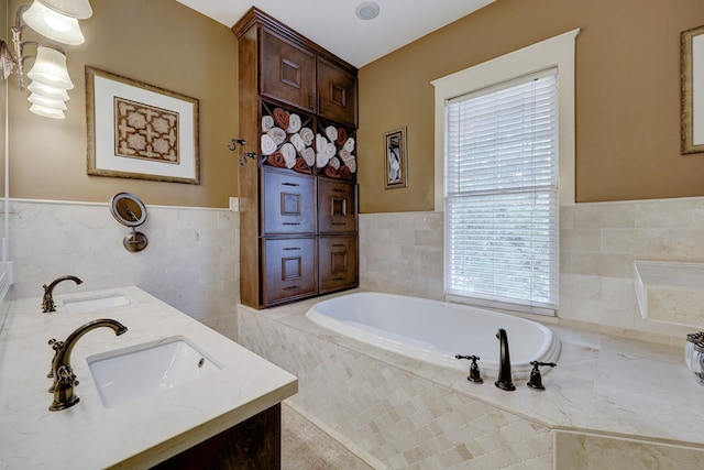 full bath with a sink, a garden tub, tile walls, and double vanity