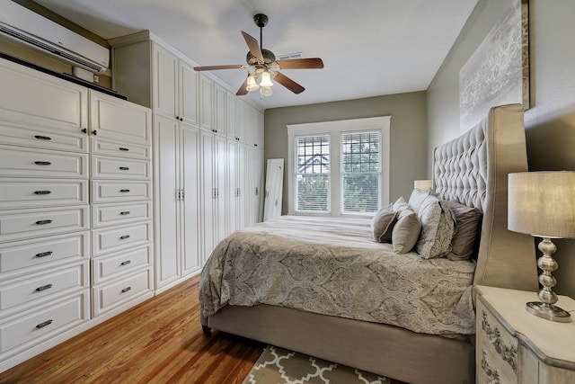 bedroom with light wood-style flooring, a wall mounted AC, and a ceiling fan