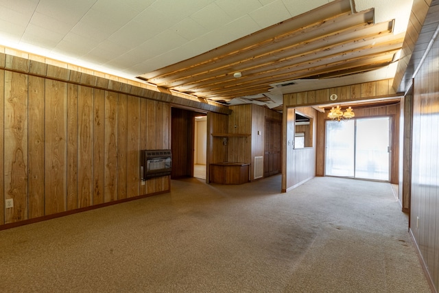 unfurnished living room featuring wooden walls, visible vents, heating unit, carpet, and a chandelier