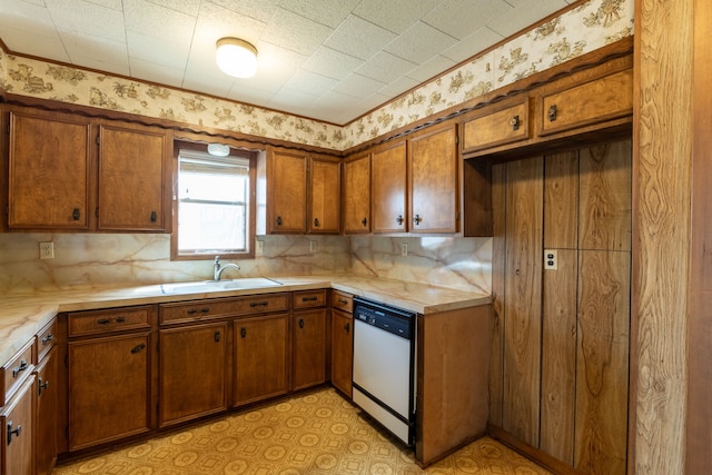 kitchen with tasteful backsplash, light countertops, brown cabinetry, a sink, and dishwasher