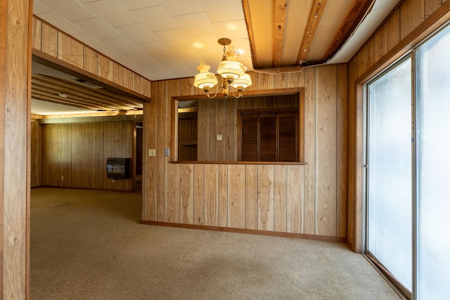 interior space featuring carpet, a notable chandelier, heating unit, wooden walls, and baseboards