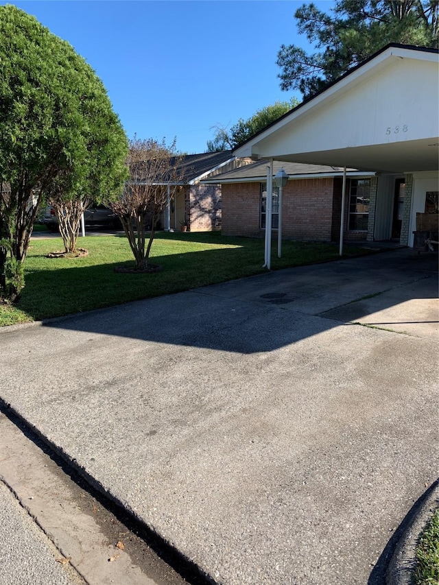 view of home's exterior with driveway, brick siding, and a lawn