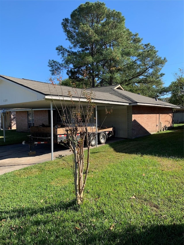 view of side of property featuring a garage, brick siding, a lawn, and a carport