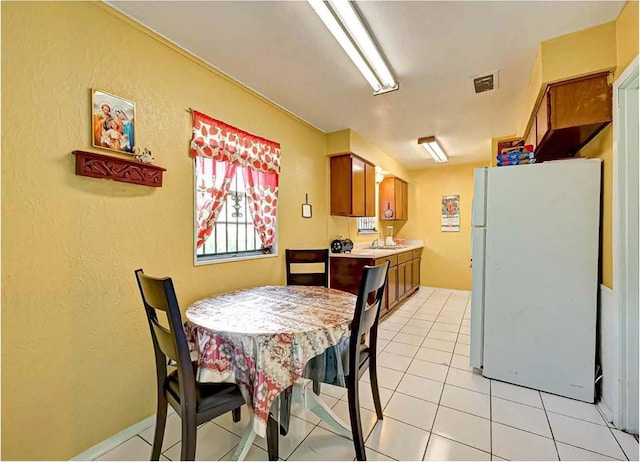 dining area featuring a textured wall, visible vents, and light tile patterned flooring