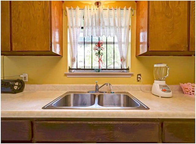 kitchen featuring light countertops, a sink, and brown cabinets