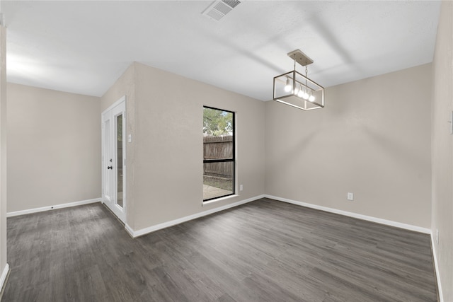 spare room featuring a chandelier, dark wood-style flooring, visible vents, and baseboards