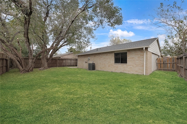 back of house featuring central AC unit, a fenced backyard, roof with shingles, a yard, and brick siding