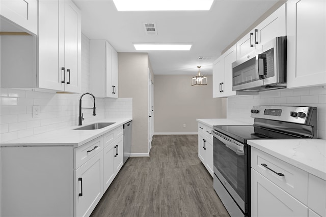 kitchen featuring a sink, white cabinets, appliances with stainless steel finishes, light stone countertops, and dark wood finished floors