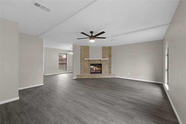 unfurnished living room featuring ceiling fan, dark wood-style flooring, visible vents, baseboards, and a brick fireplace