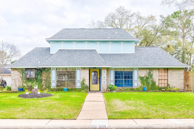 view of front of house with a shingled roof and a front lawn