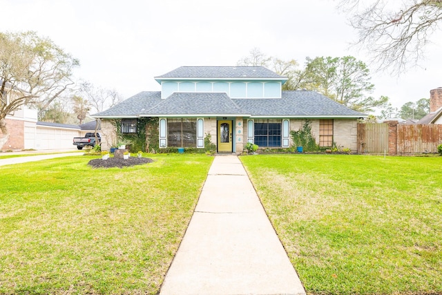 view of front of home with roof with shingles, fence, and a front lawn