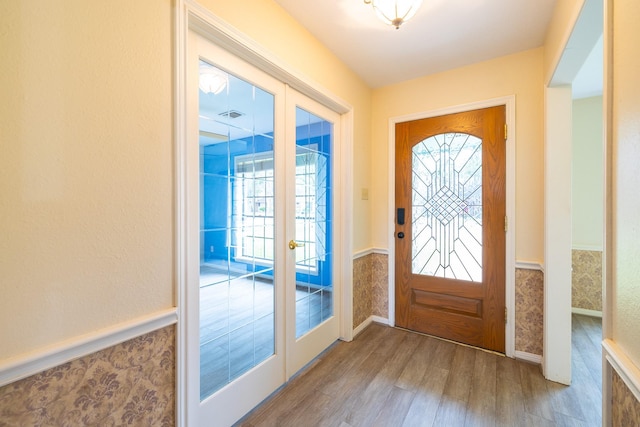 entrance foyer featuring visible vents, french doors, wood finished floors, and wainscoting