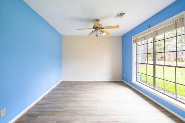 unfurnished room featuring light wood-type flooring, baseboards, visible vents, and ceiling fan