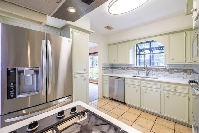 kitchen featuring light countertops, decorative backsplash, appliances with stainless steel finishes, light tile patterned flooring, and a sink