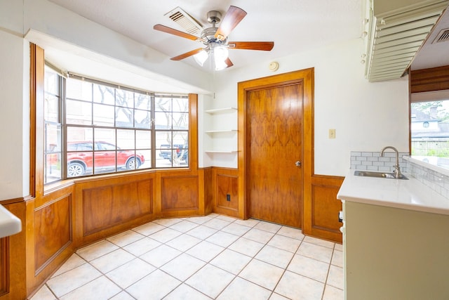 interior space with wood walls, ceiling fan, light tile patterned floors, and wainscoting