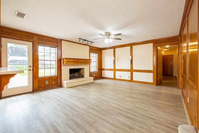 unfurnished living room featuring light wood-style flooring, a fireplace, visible vents, and a ceiling fan