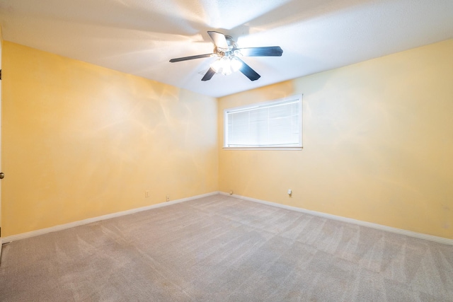 carpeted spare room with ceiling fan and baseboards