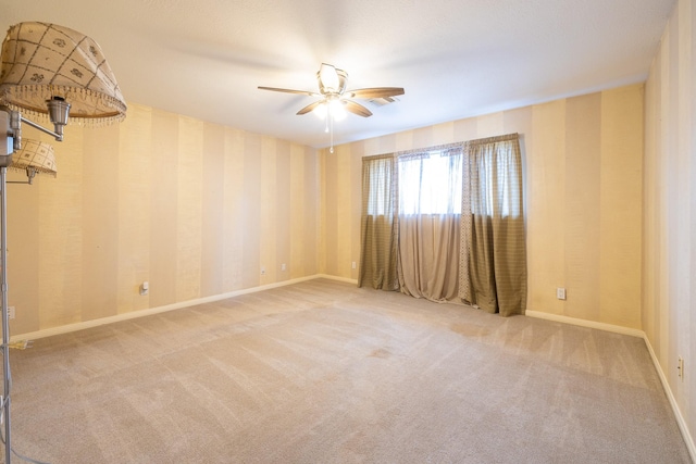 carpeted empty room with baseboards, ceiling fan, and wallpapered walls