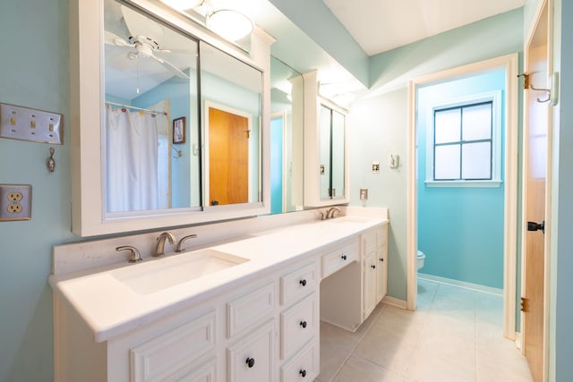 bathroom featuring toilet, double vanity, a ceiling fan, and a sink