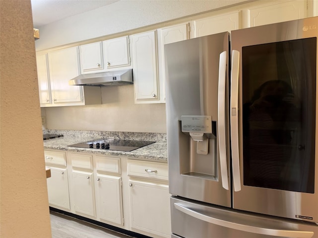 kitchen featuring light wood-style floors, white cabinetry, stainless steel fridge, under cabinet range hood, and black electric cooktop