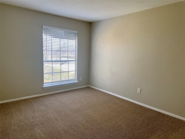 carpeted spare room featuring baseboards