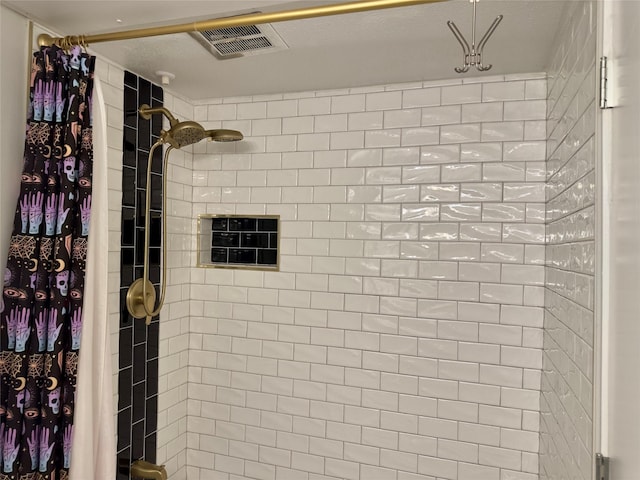 bathroom with a tile shower and visible vents