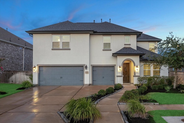 traditional home featuring a garage, driveway, fence, and stucco siding