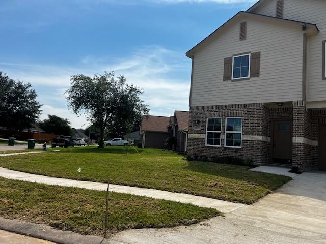 view of side of property with brick siding and a lawn