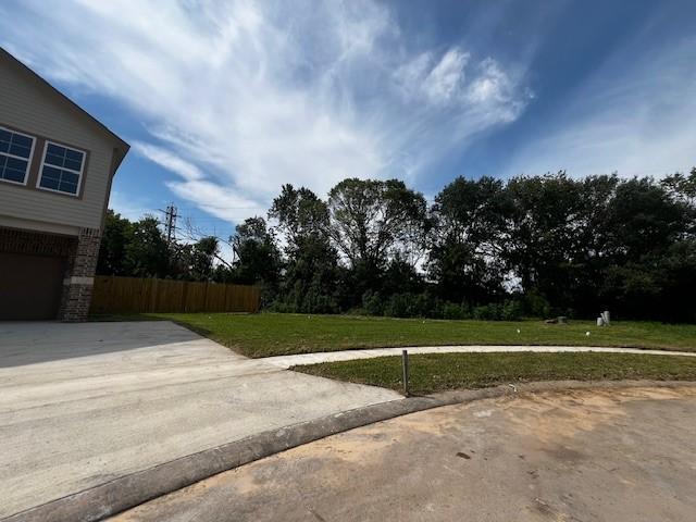 view of yard with driveway, a garage, and fence