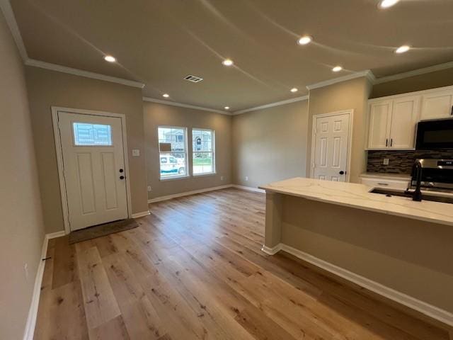 kitchen featuring visible vents, white cabinets, light wood-style floors, black microwave, and backsplash