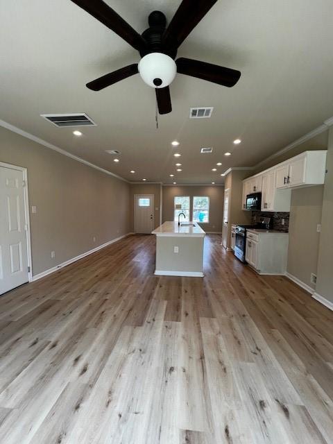 kitchen featuring black microwave, visible vents, open floor plan, ornamental molding, and stainless steel electric range