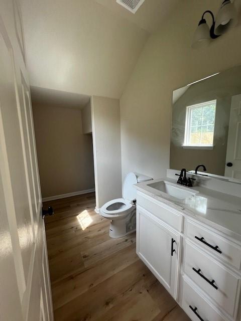 bathroom featuring visible vents, toilet, wood finished floors, vaulted ceiling, and vanity