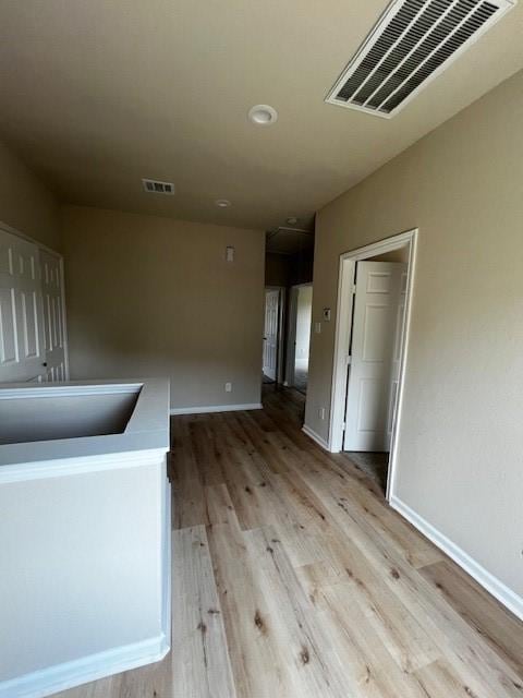 interior space featuring light wood-style floors, baseboards, visible vents, and a sink